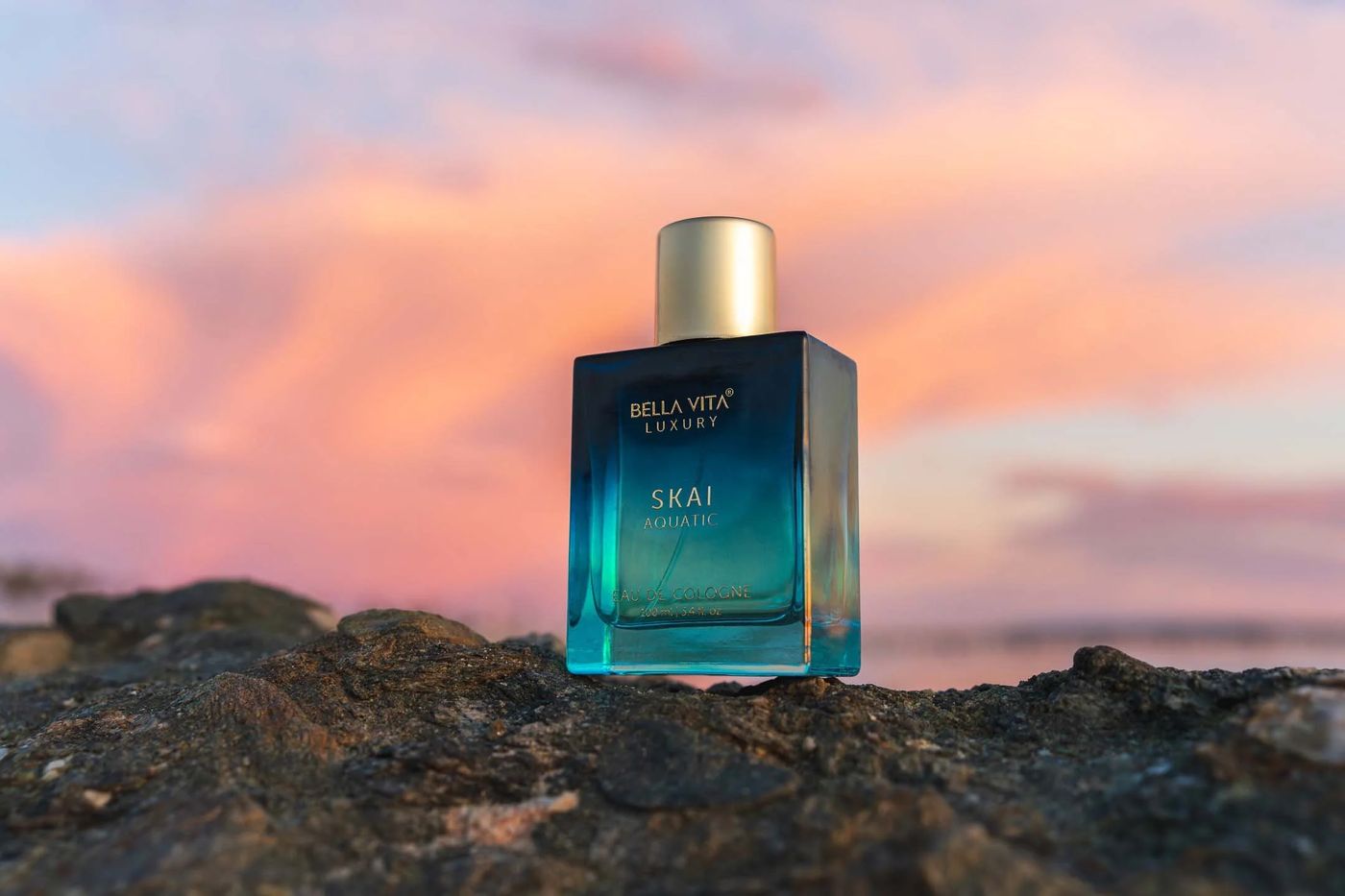 Original photo of a perfume bottle on rocks at sunset, before background removal